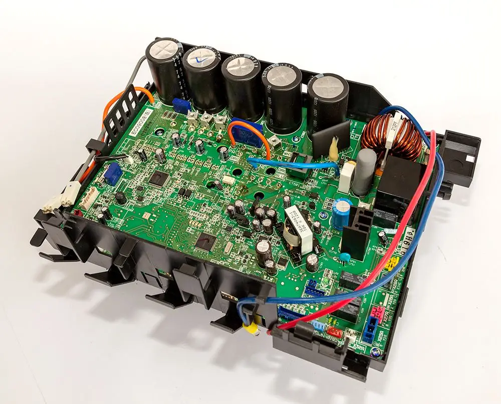 Platine von Daikin mit verschiedenen elektronischen Komponenten, darunter Kondensatoren, Widerstände und Anschlussklemmen, auf schwarzem Trägermaterial.